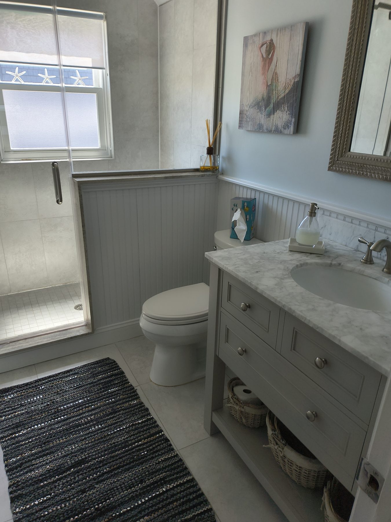 Bathroom with glass shower and gray paneling