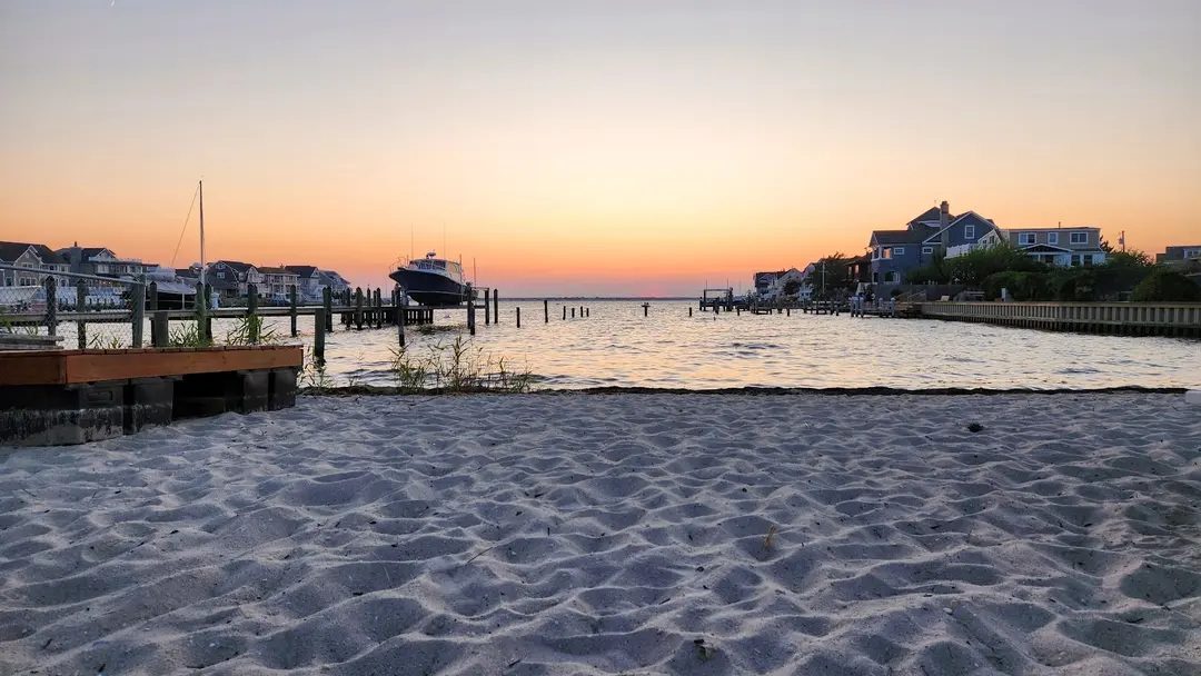 Barnegat Bay at sunset, with a dock, a boat, and houses across the water