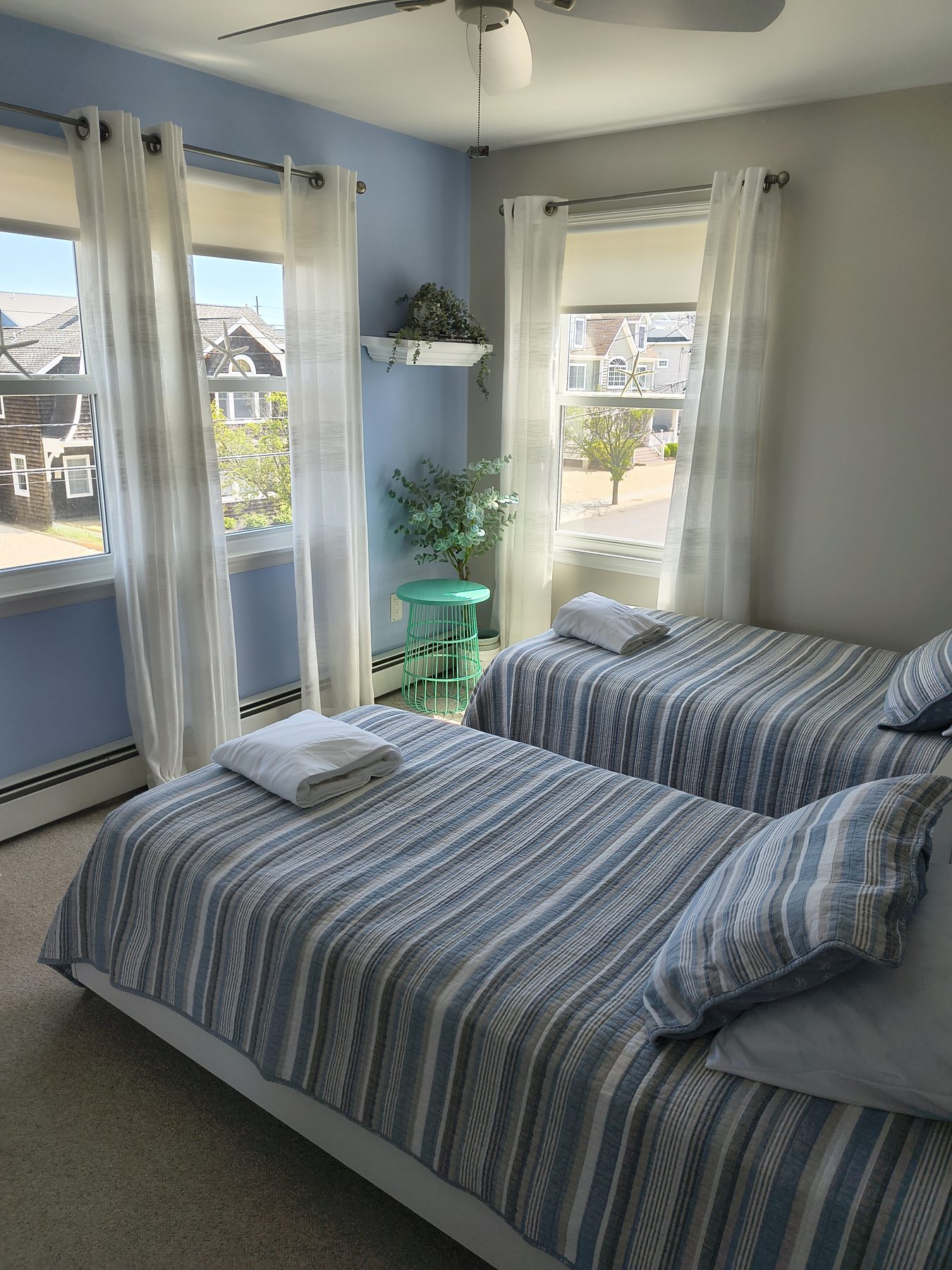 Twin bedroom with blue striped quilts and mint side table