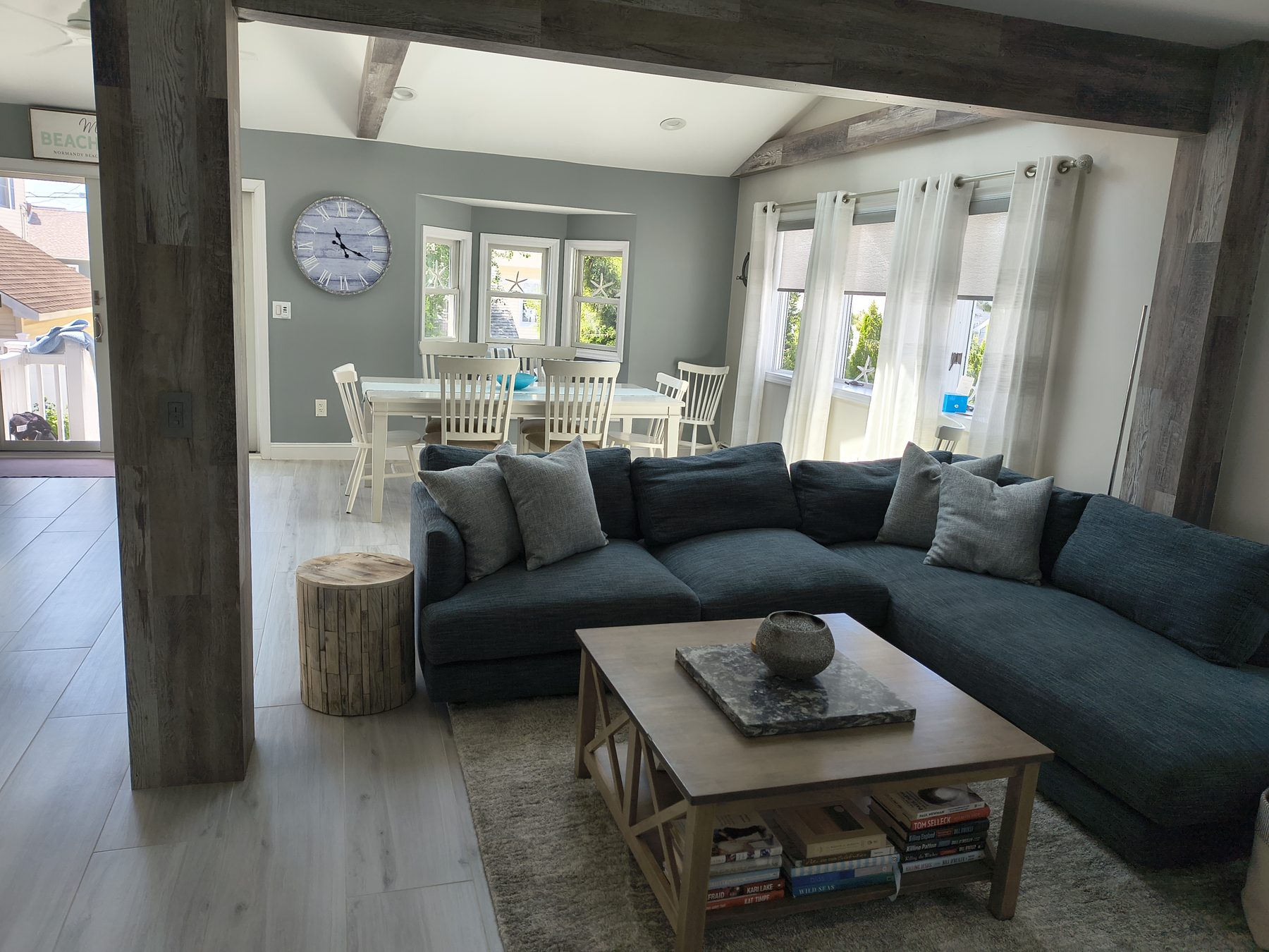 Open-plan living and dining with blue sectional and wood beams