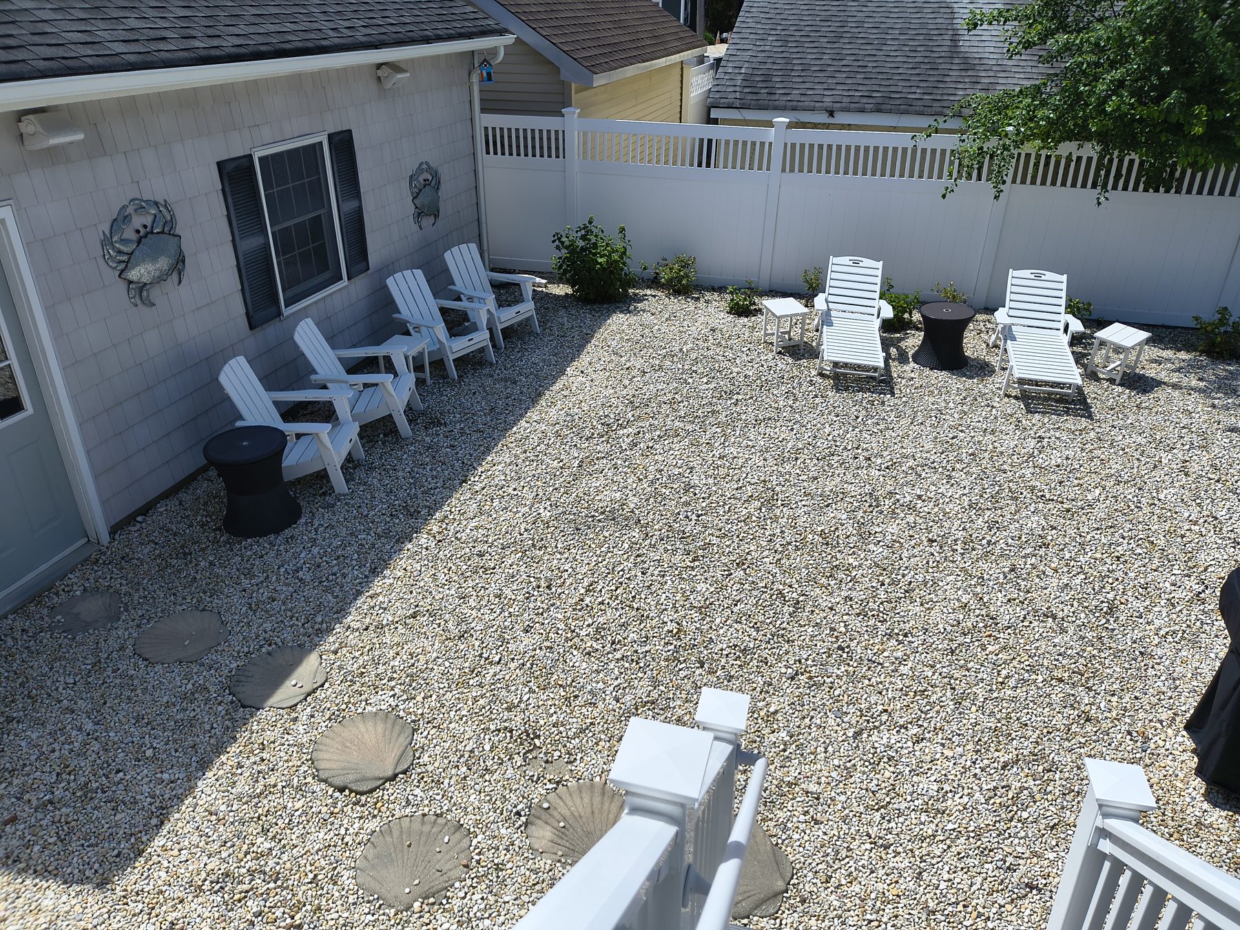 Pebble courtyard with white Adirondack chairs and shell stepping stones